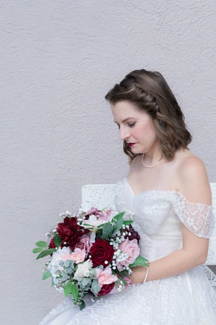 Bride smiling at her bouquet during bridal photos at her Omaha wedding