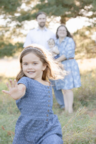 A young girl running toward the camera during a light & airy family session in Omaha